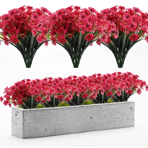 Close-up of artificial red violets in a grey concrete planter against a white background