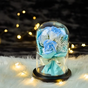 Blue soap rose bouquet in a glass dome with LED lights on a white fur surface