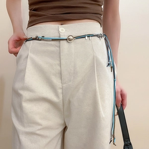 Detail of bohemian hand-woven suede belt featuring metallic charms and leaf pendants