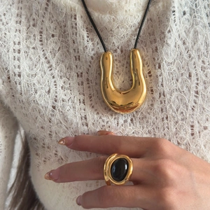 Detail of a 18k gold plated U-shaped necklace and vintage malachite ring on a model