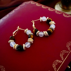 Vintage gold hoop earrings with brown tiger eye beads and purple stones on red leather