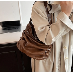 Dettaglio di una borsa hobo in vernice marrone scuro con eleganti dettagli arricciati