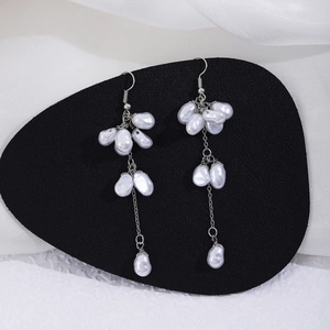 Detail of long fringe pearl drop earrings with butterfly design on a black velvet stand