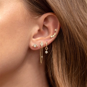 Close-up of gold chain fringe and eye-shaped stud earrings with colorful zircon stones
