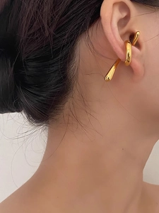 Close-up of golden liquid metal ear cuff with organic twisted design on model ear