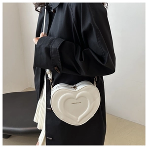 Detail view of a white heart-shaped crossbody bag with embossed texture and FASHION logo