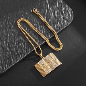 Macro detail of a gold holy bible pendant necklace featuring a cross and clear rhinestones