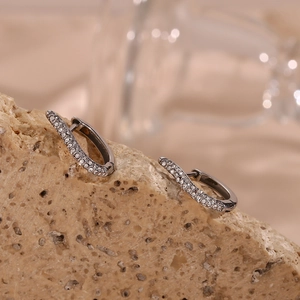 Close-up of gunmetal swirl earrings with sparkling white zircons on natural stone