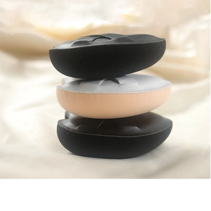 Vertical stack of three thick marshmallow makeup sponges on soft beige fabric background