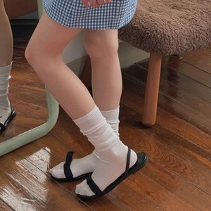 Styling detail of black strappy flat sandals worn with white mid-calf socks for a Japanese look