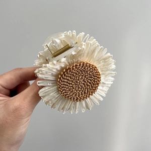 Close-up of off-white flower hair claw clip with brown woven raffia center detail