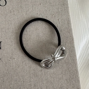 Detailed shot of a silver metallic bow charm on a high-elastic black hair tie