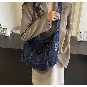 Détail d'un sac à bandoulière en denim bleu avec bords usés et surpiqûres visibles