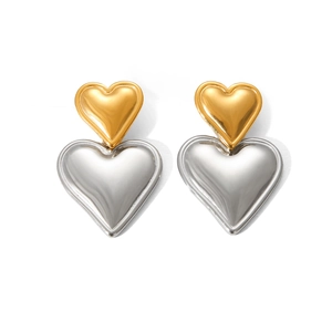 Macro shot of two-tone gold and silver heart-shaped stainless steel earrings on white