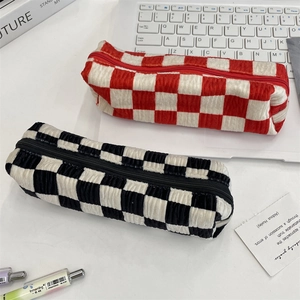 Checkered corduroy pencil cases in black and red on a desk with office supplies