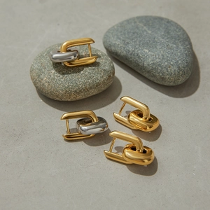 Detailed shot of two-tone and gold U-shaped link earrings on natural stones