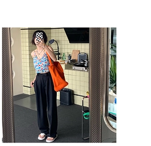 Mirror selfie showing a woman wearing a casual orange tote bag with floral top and black pants