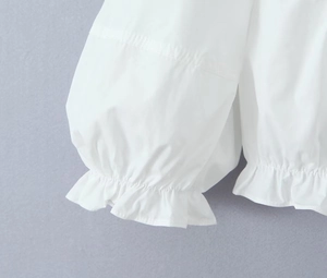 Close-up of elegant ruffled cuffs on white bubble sleeve shirt with detailed stitching