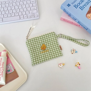 Close-up of green gingham fabric coin pouch with cute cheese embroidery and ribbon detail