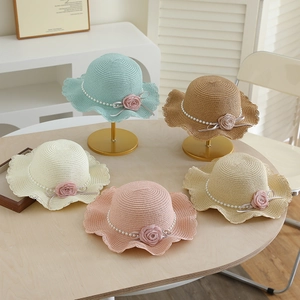 Detail view of girls' straw sun hats featuring fabric roses, pearls and ribbon accents