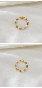 Detail of beaded rings featuring 18K gold beads and natural freshwater pearls on white fabric