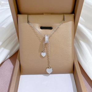 Detailed view of silver Y-necklace with cubic zirconia slider and heart charms