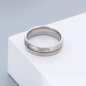 Macro shot of minimalist silver stainless steel ring with hammered texture and black inlay
