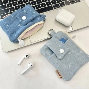 Blue denim mini card holder with star embroidery next to a laptop and wireless earbuds