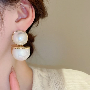 Détail des boucles d'oreilles double perle ronde avec bordure dorée sur un mannequin