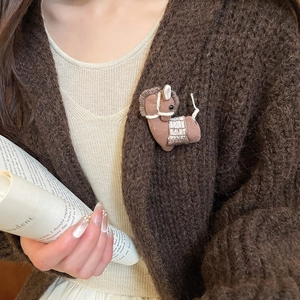 Detailed close-up of a handmade brown fabric horse brooch with white stitch embroidery