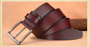 Detailed view of deep brown leather belt with vintage bronze pin buckle and natural texture