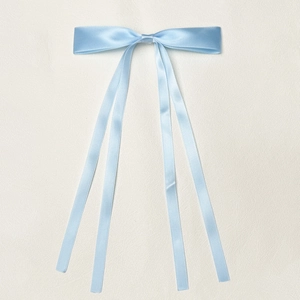 Light blue satin ribbon hair clip with long streamers on textured background