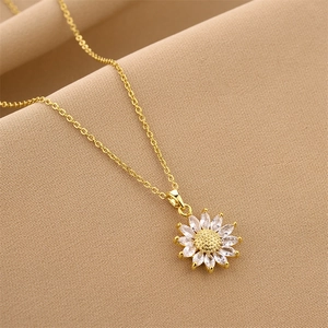 Golden titanium sunflower pendant necklace with sparkling cubic zirconia on a warm fabric