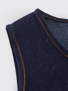 Detail of dark blue denim fabric with double orange stitching on neckline edges