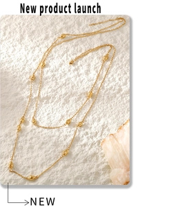 Macro detail of gold layered sweater necklace featuring oval metallic bean charms