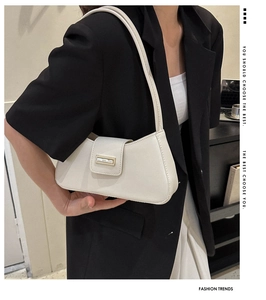 Close-up of cream PU leather baguette bag with gold buckle on a black suit model
