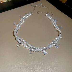 Macro shot of double-layered pearl necklace with clear teardrop zircon pendants