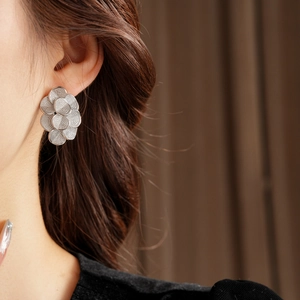 Gros plan détaillé d'une boucle d'oreille fleurie argentée avec pétales en métal texturé