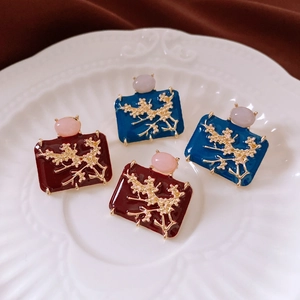 Detailed close-up of vintage enamel plum blossom earrings in red and blue colors