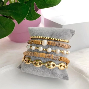 5-piece bohemian bracelet set with pearls, gold beads, and heishi discs on a display pillow