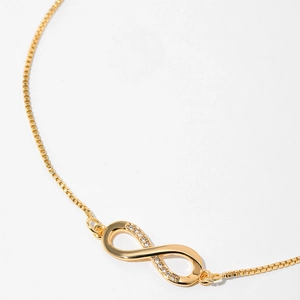 Macro shot of gold-plated infinity pendant with micro-set zircon and box chain details