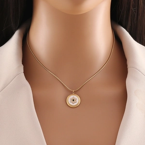Golden round pendant pearl necklace set with shell inlay on a model neck with a blazer