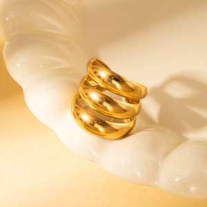 Detailed view of a gold triple-layer spiral ring on a wave-pattern ceramic tray