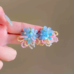 Close-up of handmade beaded floral earrings with blue petals and colorful seed bead tassels