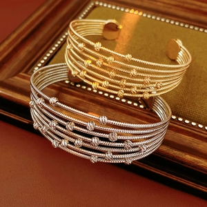 Détail d'un bracelet manchette multicouche à perles doré et argenté sur socle vintage