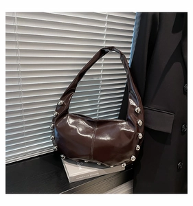 Macro view of dark brown patent leather shoulder bag with metallic silver rivet details