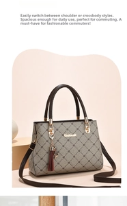 Close-up of gray patterned handbag with a red tassel charm and metallic brand logo