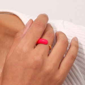 Close-up of golden adjustable open ring with vibrant pink enamel teardrop on finger