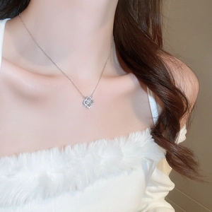 Close-up of a silver clover pendant necklace with zircon stones worn by a model