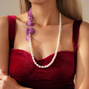 Elegant pearl necklace featuring purple chiffon flowers worn by a model in velvet dress